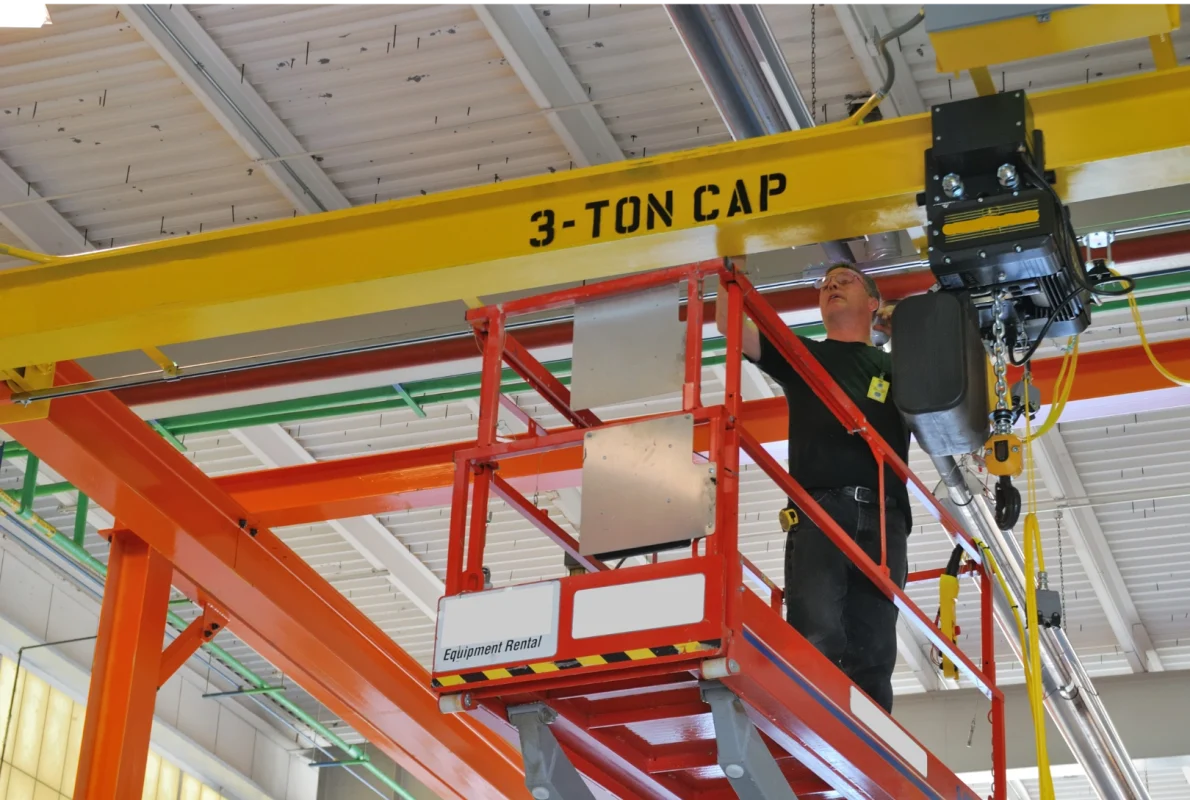 Operator suwnicy w odzieży ostrzegawczej i butach ochronnych podczas kontroli urządzenia