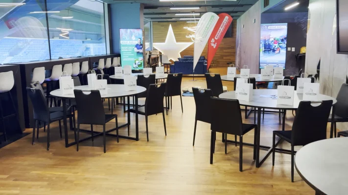 Sala konferencyjna z okrągłymi stołami i materiałami, przygotowana na szkolenie.